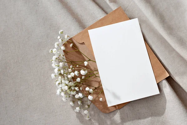 Blank paper card, postcard, envelope and flowers on a neutral background, congratulation postcard or letter floral template with copy space