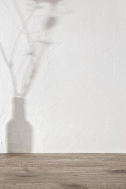 Estetik güneş ışığı gölgeleri, beyaz desenli duvarda vazo şeklinde çiçekler ve bej ahşap zemin, ev odası iç ürünü için boş şablon, markalaştırma gösterisi için arka plan, kopyalama alanı