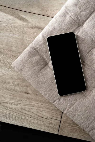 Tarafsız bir iç bej yastıkta cep telefonu ve ahşap masa, zarif minimalist ticari şablon, kopyalama alanı.