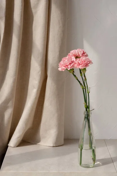審美的なインテリアの花の組成 ベージュのテーブル上の花瓶にカーネーションの花の花束 リネンカーテンと白い壁の背景 エレガントなミニマリスト現代の家の装飾 — ストック写真