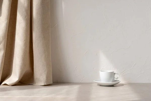 審美的なミニマリストニュートラルホームインテリアの背景 空の白い壁 ベージュリネンカーテン 石のテーブルトップ 太陽の光の下でコーヒーカップ — ストック写真