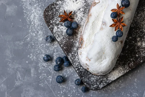 Christstollen, traditional winter Christmas dessert, fruit cake baked with raisins and decorated witha blueberry, anise and sugar powder, sweet delicious festive food closeup