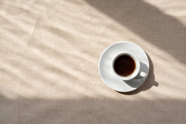 Minimalist nötr estetik arka plan, bej keten arkaplanda kahve fincanı soyut güneş ışığı gölgeleri, günaydın konsept, kopyalama alanı