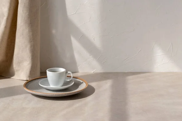 テーブルの上のコーヒーカップ 中性ベージュの家のインテリアの背景に太陽の光の影 空の白い壁のコピースペース — ストック写真