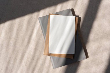 Boş kağıt kart maket, zarf, not defteri nötr bej arkaplan üzerinde soyut güneş ışığı gölgeleri, minimalist ticari şablon, kopyalama alanı