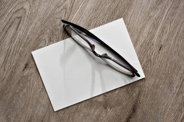 Tarafsız Bej Ahşap Masa Arkasında Boş Beyaz Kağıt Kart Gözlük — Stok fotoğraf