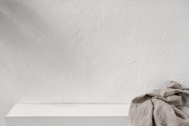 Boş beyaz desenli alçı duvar ve yumuşak soyut güneş ışığı gölgesi ve keten bej kumaşlı podyum sahne arkası. Tarafsız yaşam tarzı ürün tanıtımı.