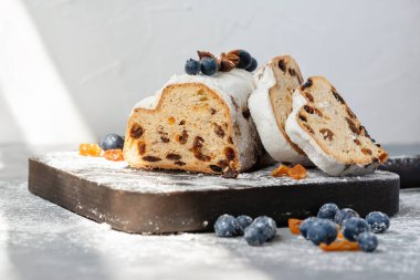 Kuru üzümlü, yaban mersinli ve şekerli tatlı bir kış tatili. Geleneksel Noel çalıntısı, tahta tahtada dilimlenmiş, güneş ışığı altında.