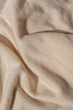 Dağınık, nötr bej örgü desenli, güneş ışığı ve gölgeli. Yumuşak örülmüş forma yün kumaş arkaplan.