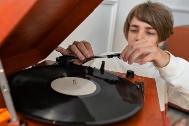 Mutlu gülümseyen yakışıklı genç çocuk retro vinil çalar, kahverengi ahşap pikap müzik, yaşam tarzı