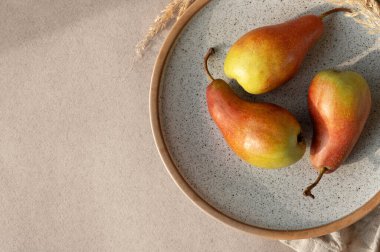 Bej masa arka planında kırmızı armutlar. Sonbahar meyveleri, yaşam tarzı