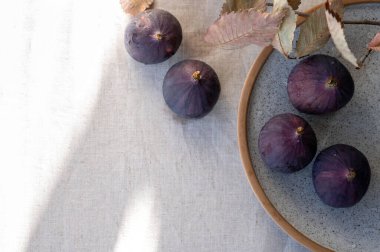 Tarafsız keten masa örtüsü üzerinde doğal güneş ışığı gölgeli bütün incir meyvesi..