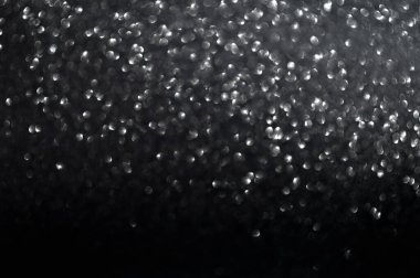 Siyah arka planda bulanık ve odaklanmış gümüş parıltısı bokeh.