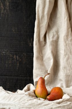 Sonbahar güzel sanatlar hala hayattadır. Kırmızı armutlar keten masa örtüsünde, siyah soyut arka planda