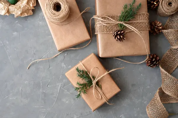 Christmas presents sustainable boxing and wrapping, holiday celebration preparing. Gift boxes in crafted paper decorated with pine tree twig, cone, hemp. Ecological design, background with copy space