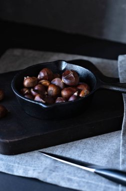 Mutfak masasının üzerinde, üzerinde gri keten masa örtüsü ve bıçakla birlikte kestane kestanesi. Geleneksel kış Noel yemekleri, ev yemekleri.