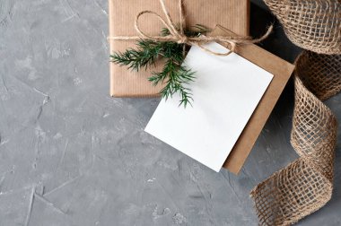 Noel hediyesi ve arka planda zarf olan tebrik kartı. Kahverengi el yapımı hediye kutusu ve fotokopi alanı, estetik marka şablonu, kırsal tarzı olan kağıt kart modeli..