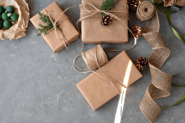 Sustainable Christmas celebration, preparation of presents. Homemade wrapping of gift boxes with craft brown paper, decoration with pine cones, twigs, jute cord. Ecological gift package.