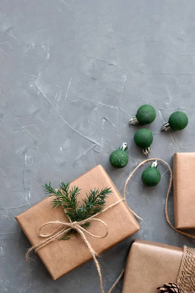 Sustainable Christmas banner, brown crafted gift boxes, presents, green crafted ornaments on gray table background. Rustic aesthetic holiday celebration concept, Scandinavian style.