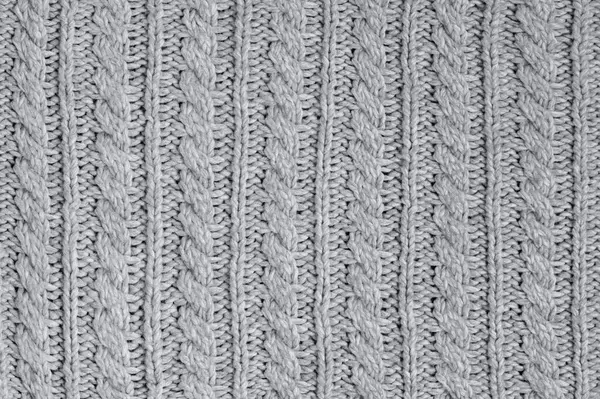 Neutral gray wool and cashmere knitwear with braid cable stitch knitted pattern, cozy winter textile background.