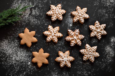 Noel zencefilli kurabiye, yıldız şeklinde geleneksel zencefilli kurabiye, siyah masa arkaplanındaki şekerle süslenmiş un. Kış tatili aile ziyafeti.