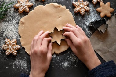 Masada unlu rulo hamur, yıldız şeklinde kurabiye bıçağı tutan eller, geleneksel Noel kurabiyesi pişirmek. Yumuşak seçici odak, yaşam tarzı.