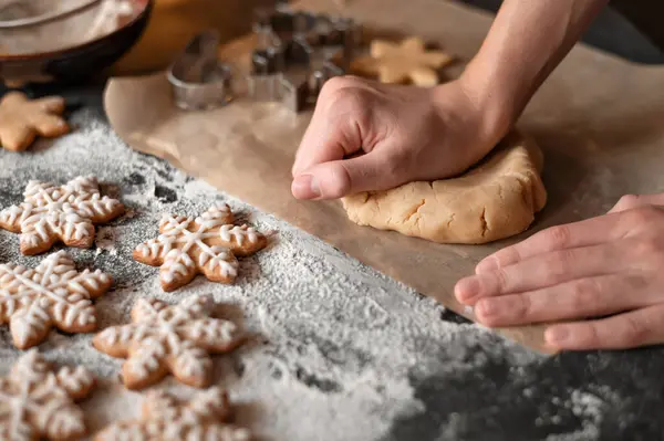 Geleneksel Noel kurabiyesi pişirme. Adamın elleri masayı un ve zencefilli krakerle yoğuruyor. Yumuşak seçici odak, yaşam tarzı.