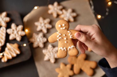 Noel tatili hazırlığı. Zencefilli kurabiye pişirmek. Çocuk elinde şekerle süslenmiş erkek şeklinde kurabiye..