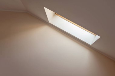 Tavan arasındaki pencereden gelen yumuşak doğal güneş ışığı, boş nötr şeftali rengi duvar arkaplanı. Minimalist ev dekorasyonu konsepti, ev doğal ışıklandırma..