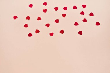 Soyut desenli, pastel pembe kağıtta küçük kırmızı konfeti kalpli. Basit ilkel Sevgililer Günü tebrik kartı tasarım şablonu.