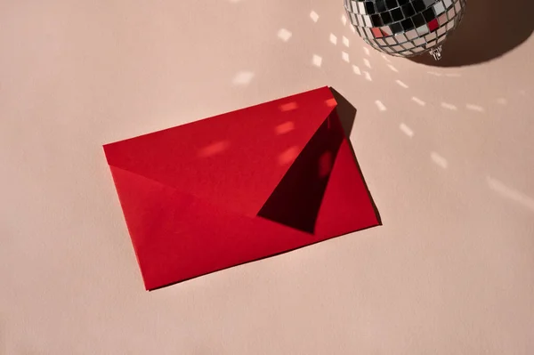 米色背景的红纸信封和闪闪发光的镜像球 光线反射 美观的最小节日贺卡 邀请函 信件概念 — 图库照片