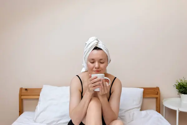 Lifestyle healthy good morning, adult woman holding coffee cup, sitting on bed, enjoying a drink, positive emotion, dopamine concept, healthy lifestyle and wellbeing.