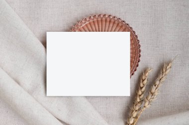 Keten kumaş üzerine boş kart modeli, dekoratif tabak ve buğday sapları, davetiye veya duyuru için estetik şablon.