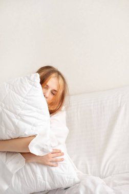 Uykulu genç kız gözleri kapalı beyaz yatak odasında beyaz yastığı kucaklıyor, gençler uyku eksikliği çekiyor, iyi bir uyku konsepti..