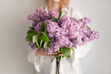 Güzel bahar leylağı buketi, elinde çiçekleri tutan kız.