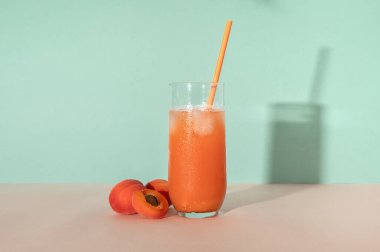 Buzlu taze kayısı suyu, ferahlatıcı yaz kokteyli. Şeftali pembesi ve turkuaz arka planda. Güneş ışığı gölgeleri, eski moda tarz..