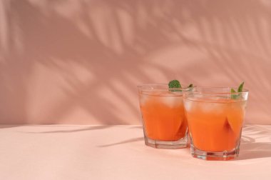 Şeftalili meyve kokteyli, pastel masa zemininde gözlüklü buzlu kokteyller tropikal palmiye yapraklı güneş ışığı gölgeleri, boş fotokopi alanı..