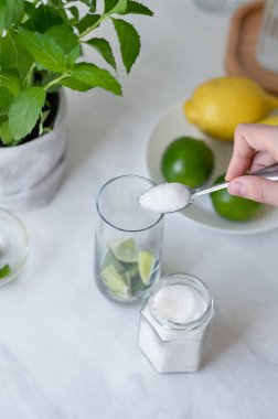 Ev yapımı mojito kokteyli hazırlama süreci, şekeri nane ve limonla bardağa koyan kişi, mojito tarifi için malzemeler.