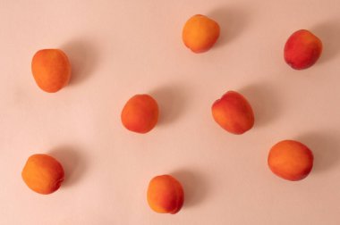 Doğal yaz yemekleri, olgun kayısı meyveleri, şeftali rengi pembe arka plan, yumuşak güneş ışığı gölgeleri..