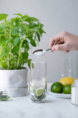 Ev yapımı mojito kokteyli hazırlama süreci, şekerli kaşık tutma, bardağa limon ve naneli şeker koyma, ev yapımı yaz içeceği pişirme tarifi..