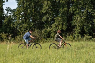 İnsanlar yaz aylarında çim biçerek bisiklet sürüyorlar..