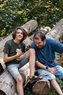 Baba ve genç oğul ormanda dinleniyor, konuşuyor ve gülümsüyor..