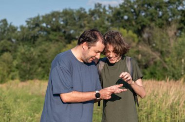 Babası ve genç oğlu kırsalda yürürken buldukları küçük bir salyangozu tutuyorlar..
