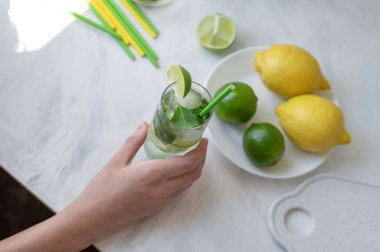 Taze yaz mojito kokteyli bardakta, limonda, limonda ve pipetle mutfak masasında, üst tarafta, yaşam tarzında..