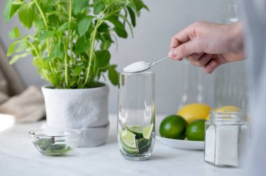 Ev yapımı yaz içeceği yapmak, limon ve nane şekerli bardağa şeker dökmek, evde mojito yapmak..