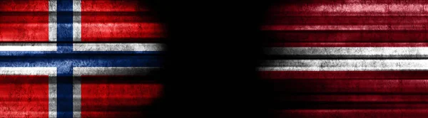 黒い背景にノルウェーとラトビアの旗 — ストック写真