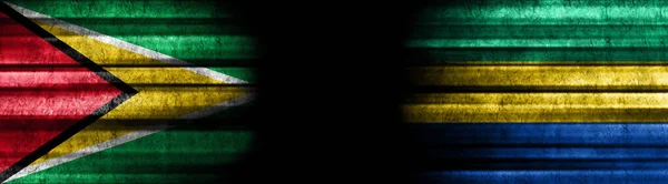 黒い背景のガイアナとガボンの旗 — ストック写真