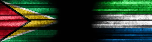 黒い背景のガイアナとシエラレオネの旗 — ストック写真