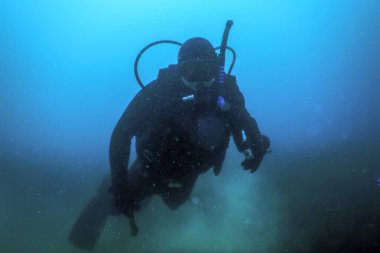 Scuba Diver Mavi Su üzerinde yüzme kameraya bakarak