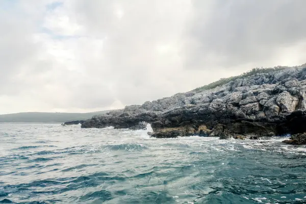 Deniz manzaralı dalgalar Rocky Shoreline, Bulutlu Gökyüzüne çarpıyor 